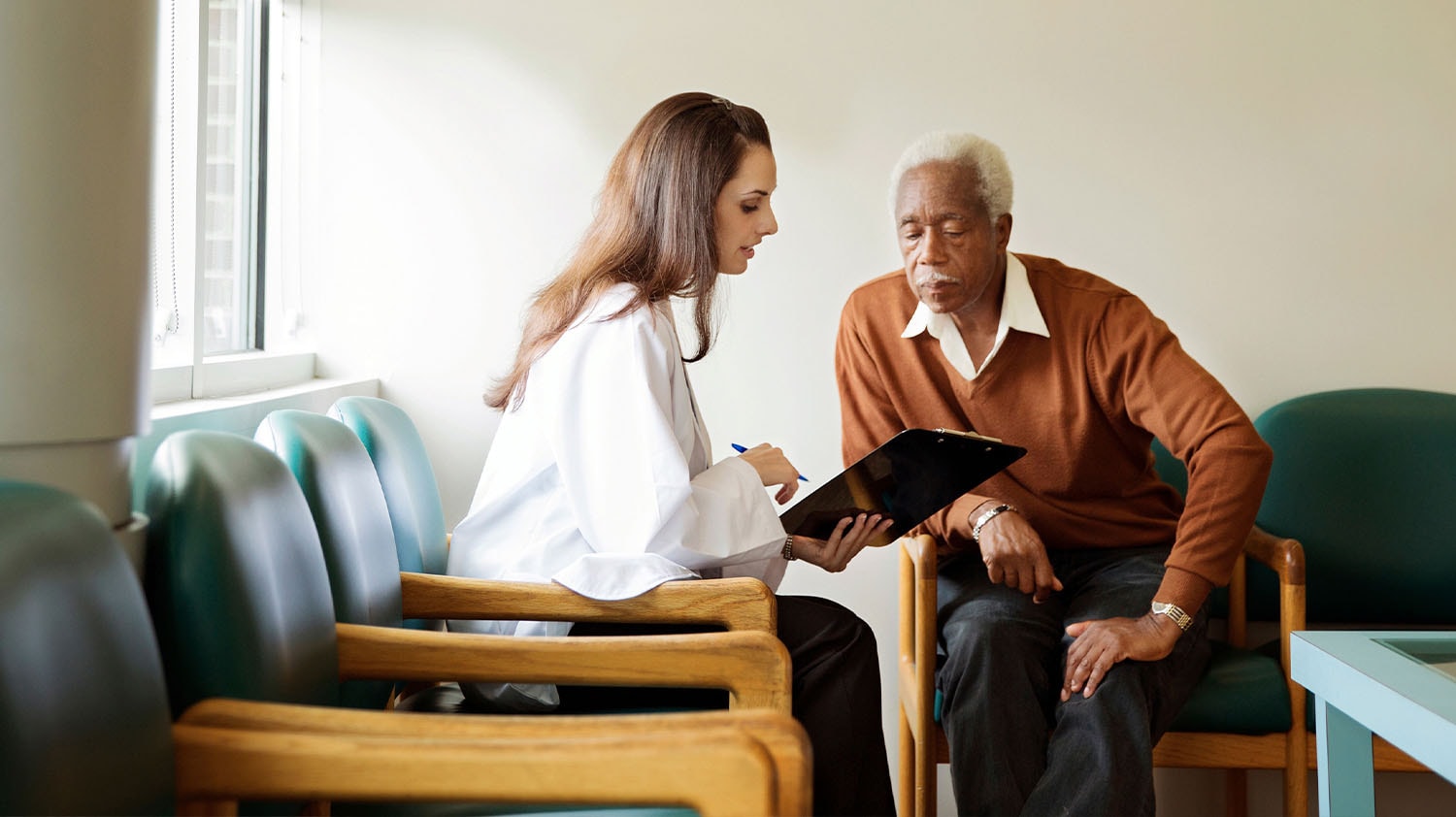 A doctor with a clipboard discussing options with a patient