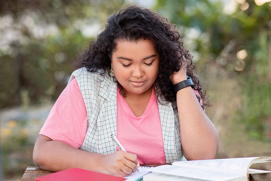 A person writing on a piece of paper on a table